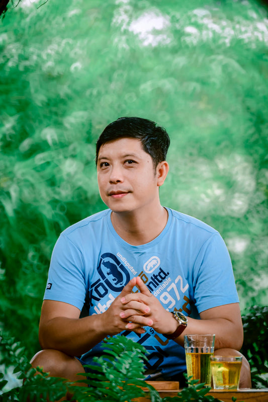 Man wearing blue Ecko Unltd t-shirt with watch, sitting outside with drinks.